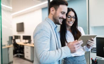 Attractive business couple using tablet in modern office