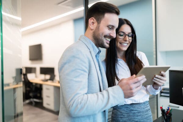 Attractive business couple using tablet in modern office