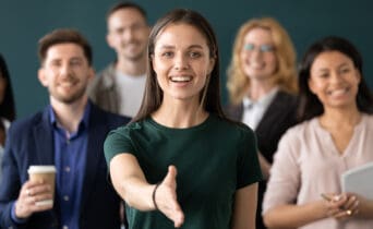 Woman company representative holds out hand for handshake welcoming client