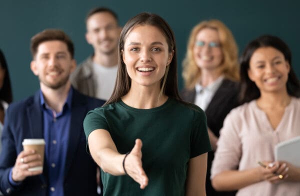 Woman company representative holds out hand for handshake welcoming client