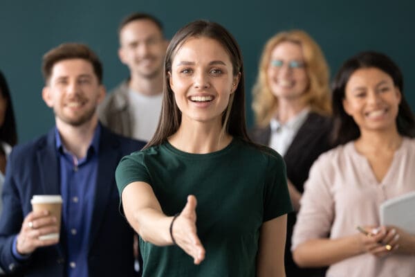 Woman company representative holds out hand for handshake welcoming client