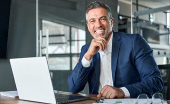 Happy middle aged business man ceo working on laptop sitting in office